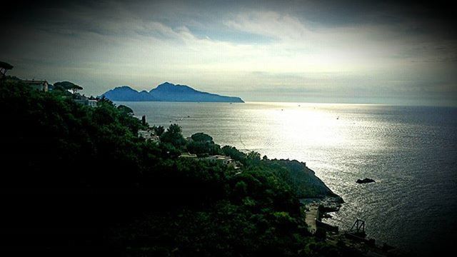 sea, water, tranquil scene, horizon over water, scenics, tranquility, sky, beauty in nature, mountain, sunset, nature, idyllic, silhouette, coastline, tree, beach, high angle view, calm, rock - object, reflection