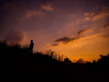 Silhouette man standing against orange sky