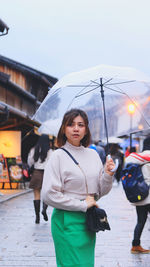 Front view of a woman holding an umbrella in the old town of kyoto.