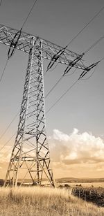 Low angle view of electricity pylon on field against sky