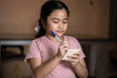 Cute girl holding mobile phone at home