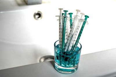 Close-up of syringes in glass on sink