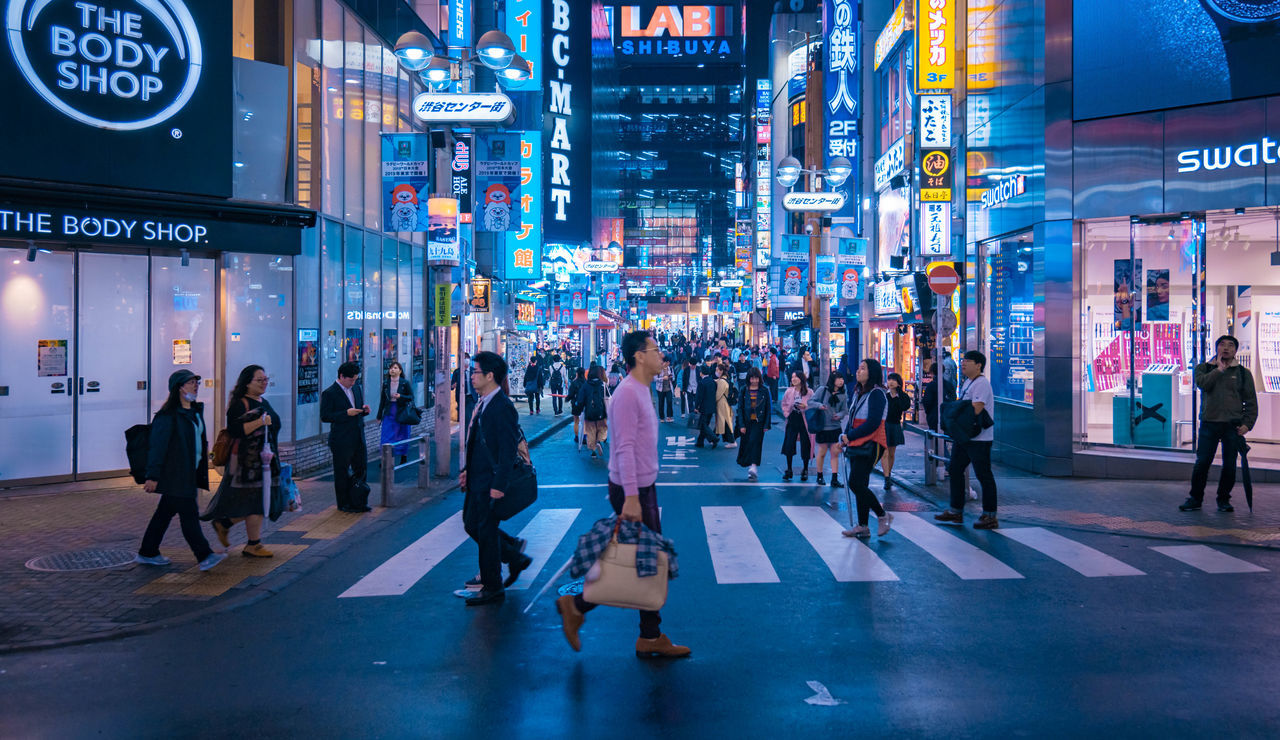 GROUP OF PEOPLE WALKING ON ROAD IN CITY