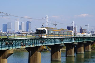 Bridge over river in city against sky