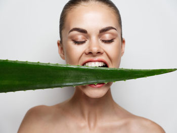 Woman biting aloe vera plant against white background