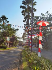 Road by palm trees against sky in city