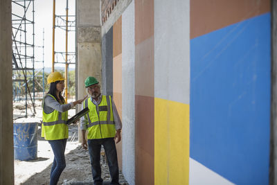 Engineer inspecting construction site, talking to workers