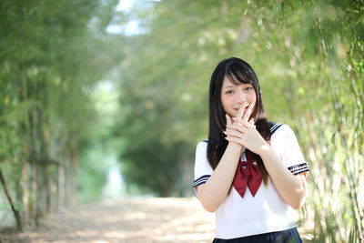 Portrait of beautiful young woman standing amidst bamboo groove