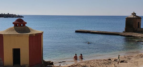 People on beach against clear sky