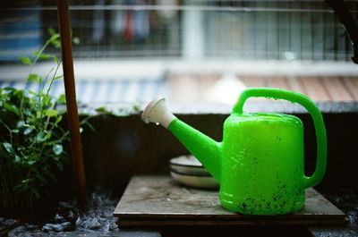Close-up of green watering can on table