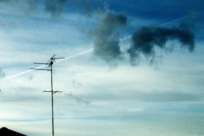 Low angle view of electricity pylon against cloudy sky