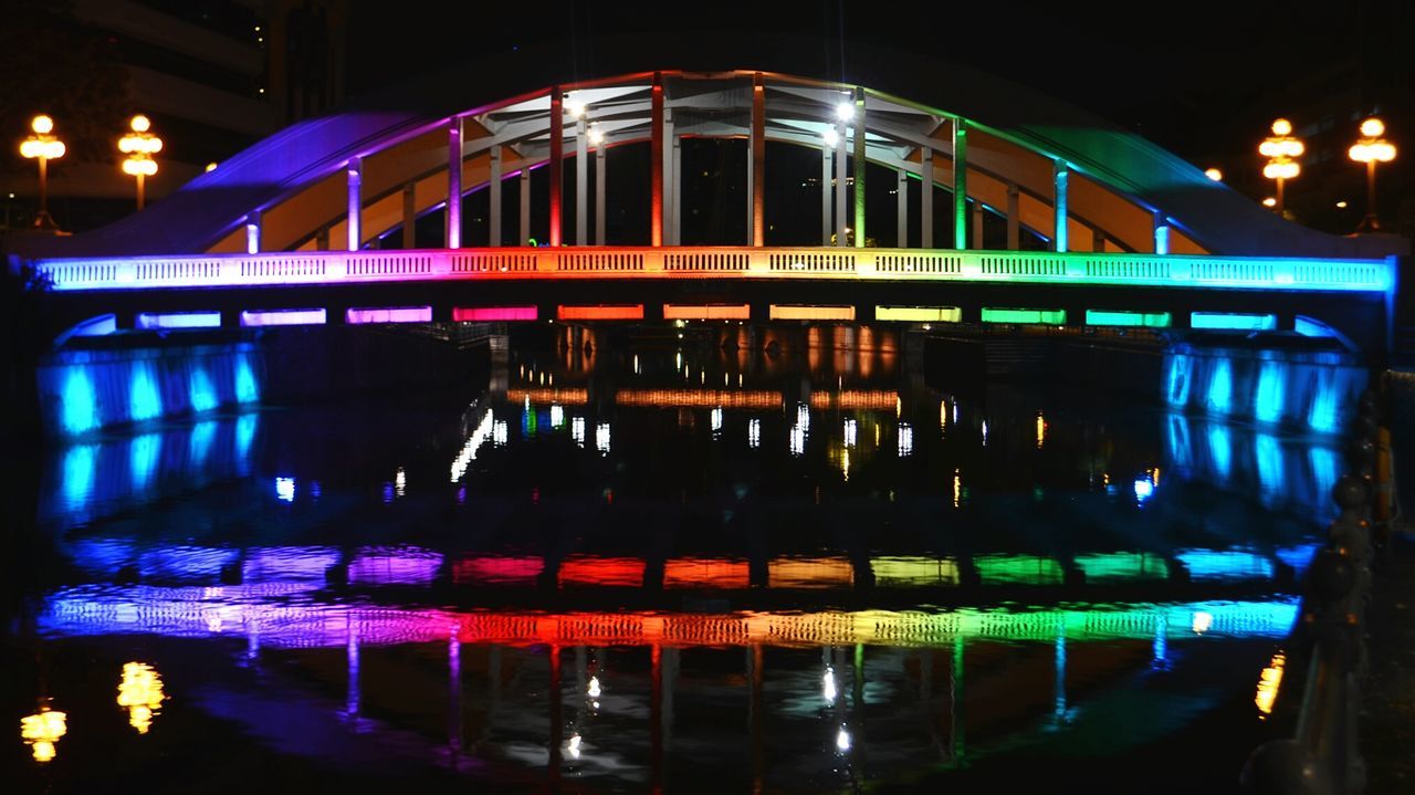 illuminated, night, reflection, water, built structure, architecture, waterfront, building exterior, city, lighting equipment, bridge - man made structure, river, light - natural phenomenon, city life, glowing, connection, incidental people, long exposure, outdoors, street light