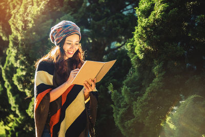 Woman reading book while standing on land