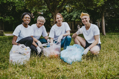 Portrait of smiling male and female volunteers crouching at park