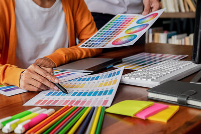 Midsection of creative business people discussing over color swatch at desk in office