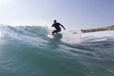 Man surfing in sea against sky