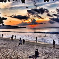 People at beach against cloudy sky