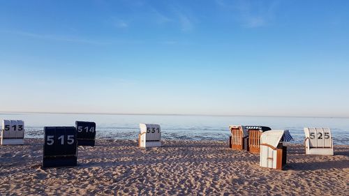 Hooded chairs on beach against sky