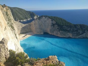 Scenic view of sea and mountains against clear blue sky