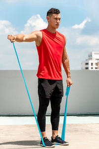 Full length of man exercising while standing against the sky