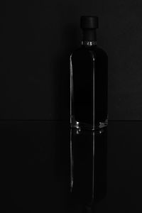 Close-up of glass bottle on table against black background