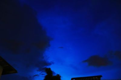 Low angle view of silhouette trees against blue sky