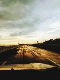 Road by street against sky during sunset