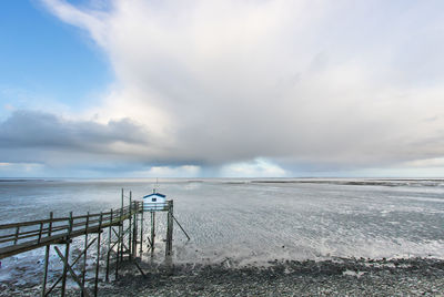 Scenic view of sea and fishing hut against sky