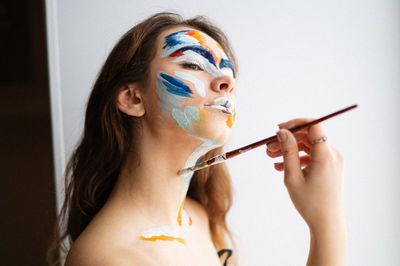 Close-up of woman painting face against wall