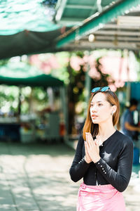 Young woman looking away while standing outdoors