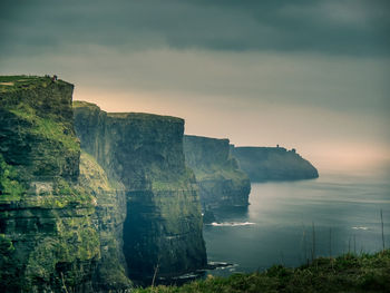 Scenic view of cliff by sea against sky