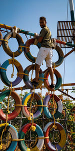 Low angle view of boy standing on metallic structure against sky