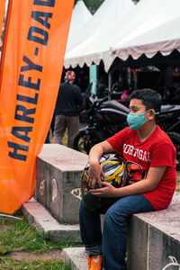 Young child sitting alone wearing face mask at the bike week event.