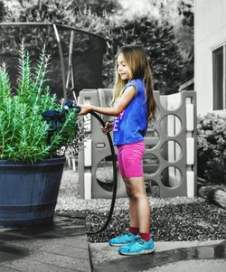 Side view of young woman standing against plants