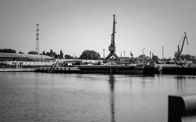 Cranes at harbor against sky