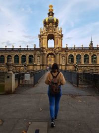 Full length rear view of woman standing against building