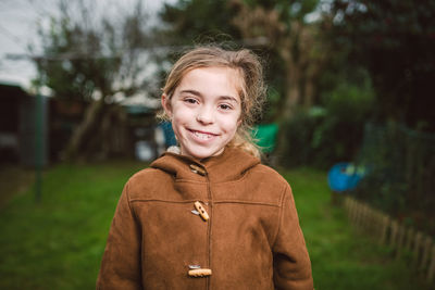 Portrait of smiling girl standing against trees