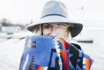 Portrait of woman wrapped in blanket standing by lake simcoe