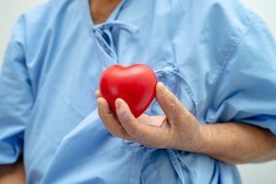 Asian senior woman patient holding red heart, healthy strong medical concept.