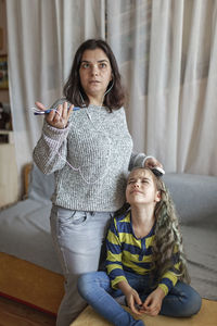 Mother combing daughters hair