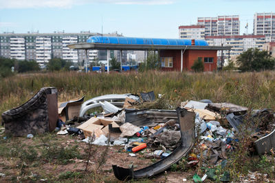 Abandoned garbage by plants against sky