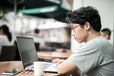 Man using mobile phone while sitting on table