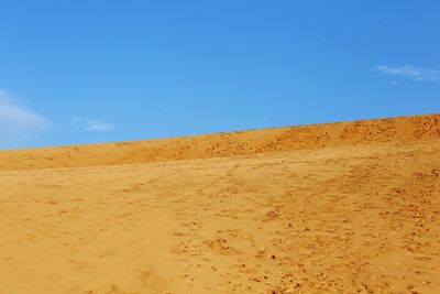 Sand dunes in desert against clear blue sky