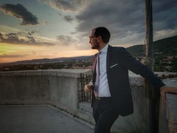 Thoughtful businessman standing against sky during sunset
