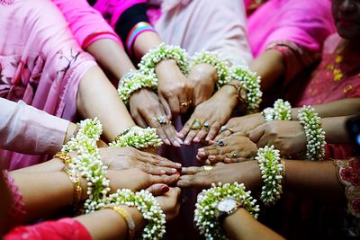 Close-up of stacked hands with flowers