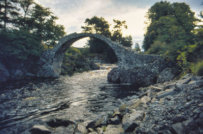 River flowing through rocks against sky