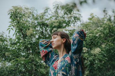 Young woman looking away against trees