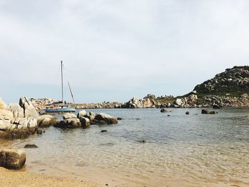 Sailboat on sea shore against sky