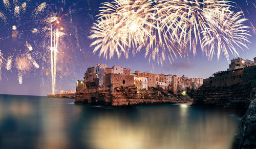 Fireworks over illuminated buildings in city at night