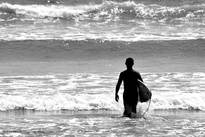 Silhouette man with surfboard walking on beach